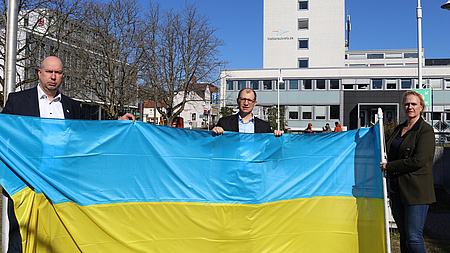 Kreisbeigeordneter Matthias Walther, Landrat Jan Weckler und Erste Kreisbeigeordnete Stephanie Becker-Bösch vor der Flagge der Ukraine
