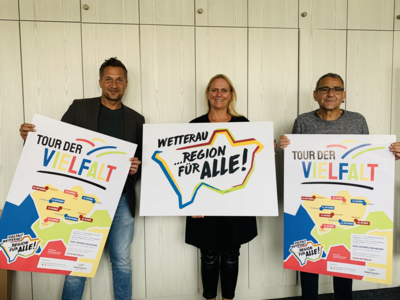 Die Erste Kreisbeigordnete Becker-Bösch und die beiden Projektmanager Becker und Thyssen halten Plakate der Tour der Vielfalt
